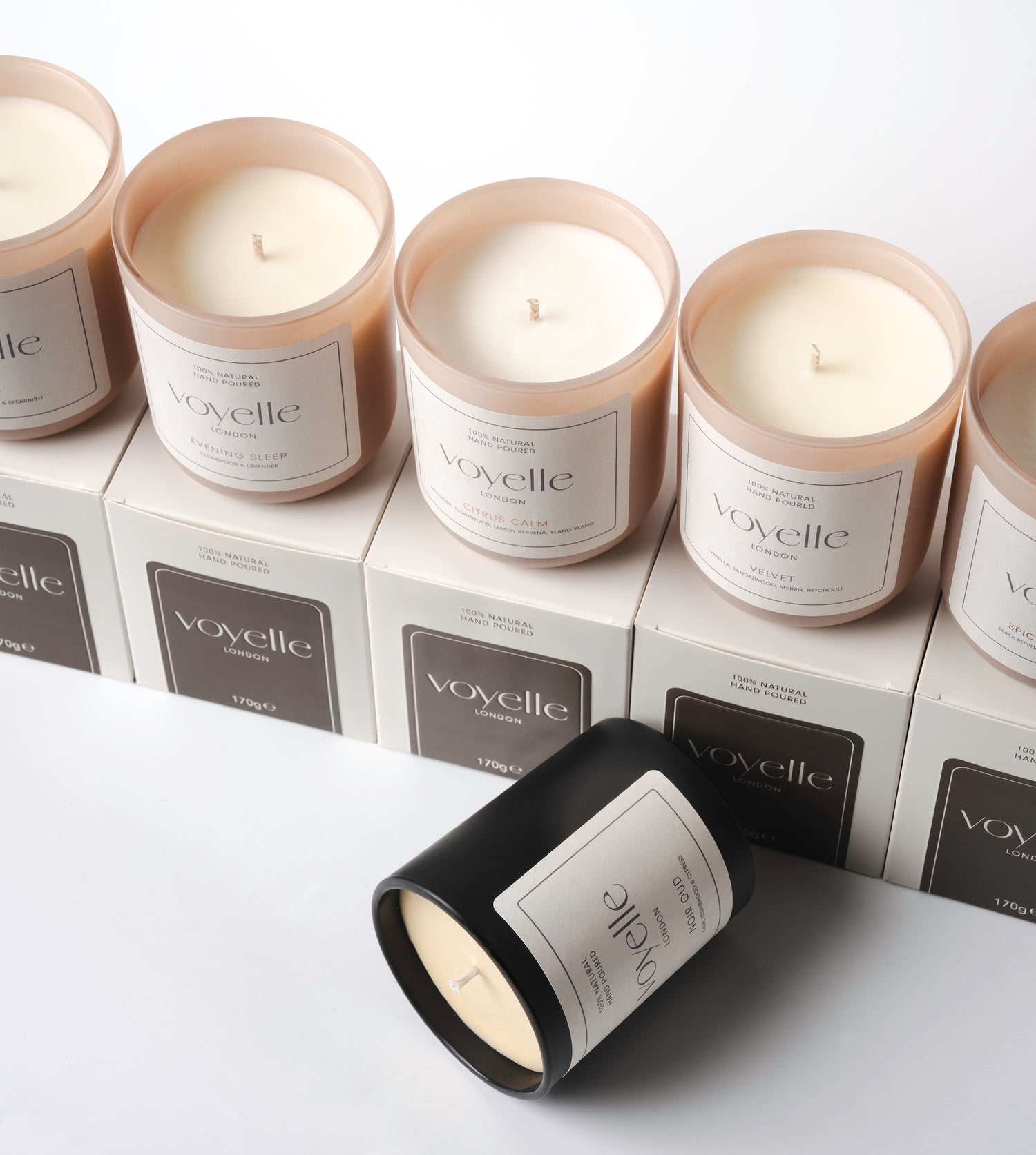 Voyelle scented candles in beige and black jars arranged on branded boxes – handmade soy wax candles for home fragrance