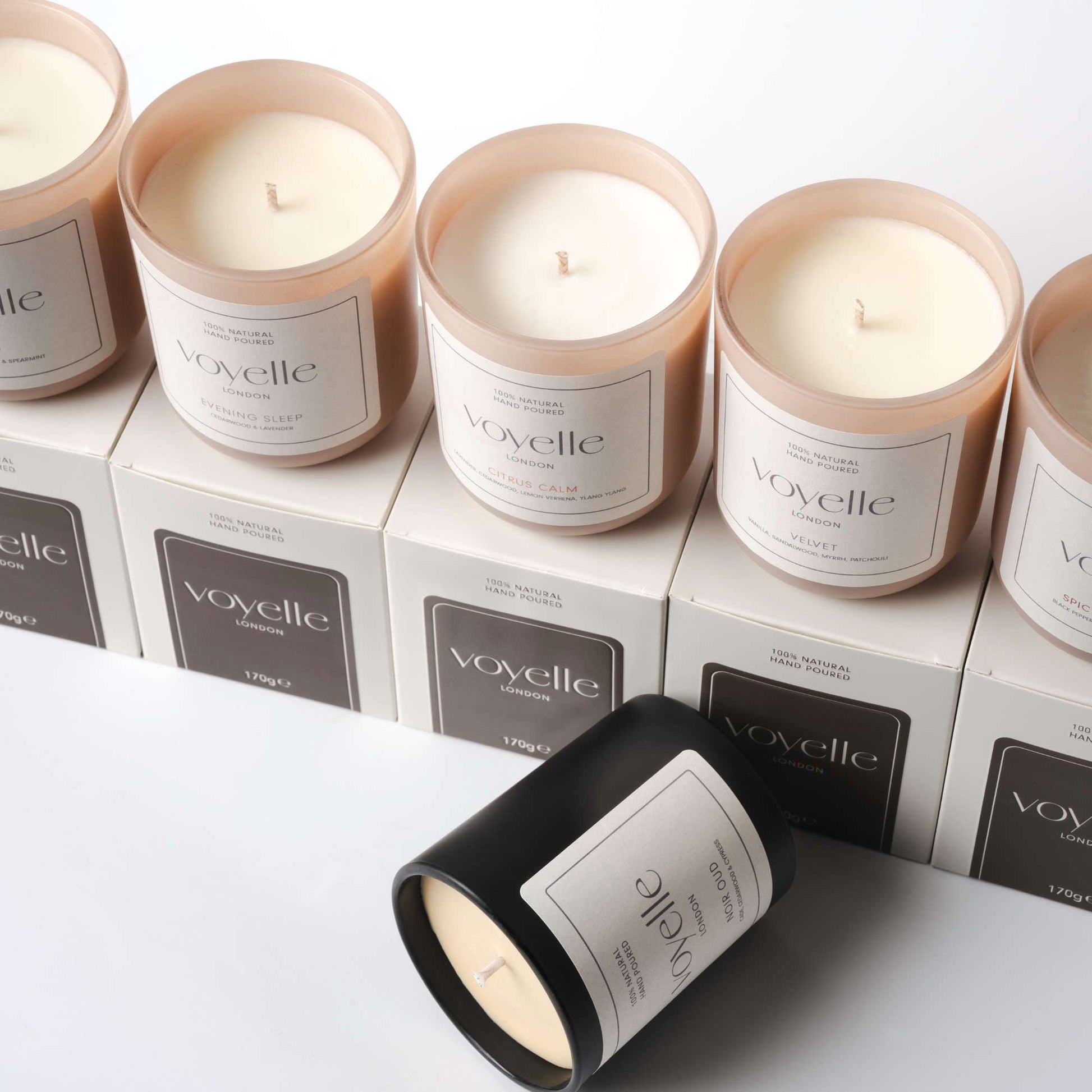 Voyelle candles arranged on branded boxes, including black and blush glass jars