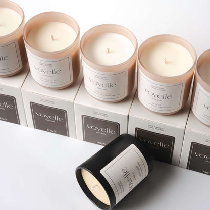 Voyelle candles arranged on branded boxes, including black and blush glass jars