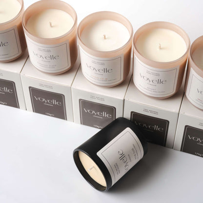 Collection of Voyelle scented candles in glass jars and packaging boxes, arranged neatly on a white background