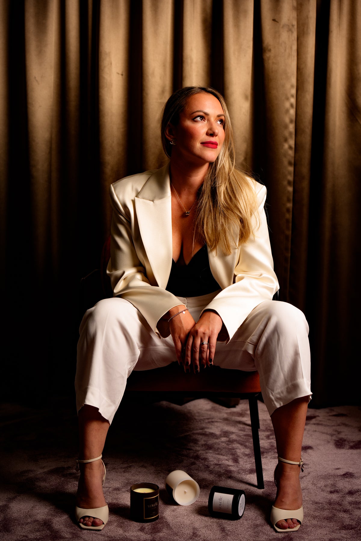 Karolina, founder of Voyelle, in a cream blazer with Voyelle candles at her feet