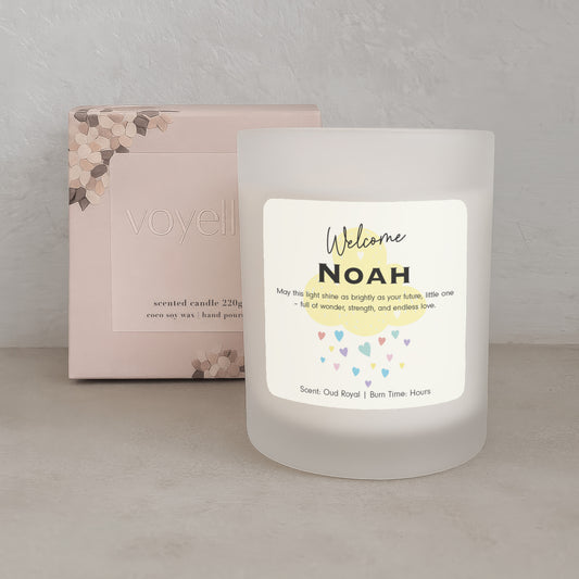 Frosted candle with 'Welcome Noah' text and colorful hearts, next to a box with 'voyell' branding.