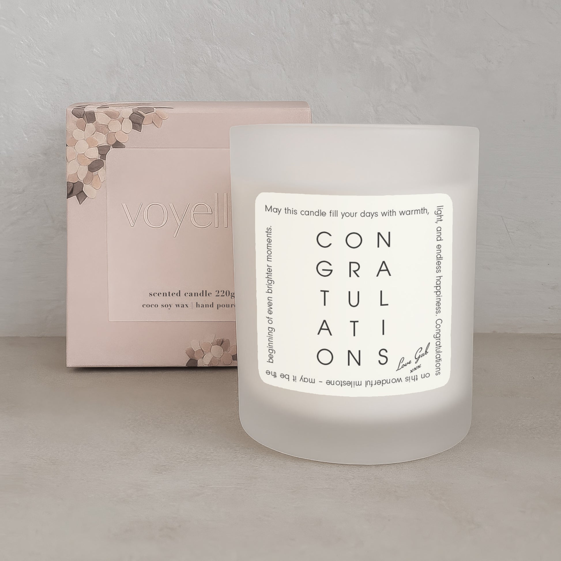 Frosted candle with 'Congratulations' message and packaging in the background