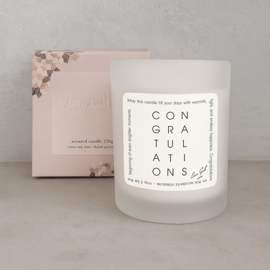 Frosted candle with 'Congratulations' message and packaging in the background