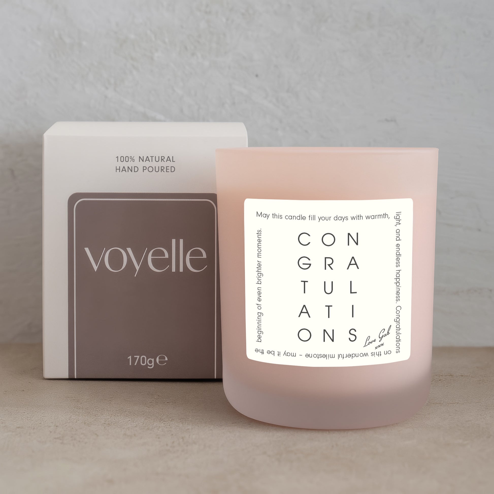 Voyelle candle with 'Congratulations' message next to its packaging on a neutral background