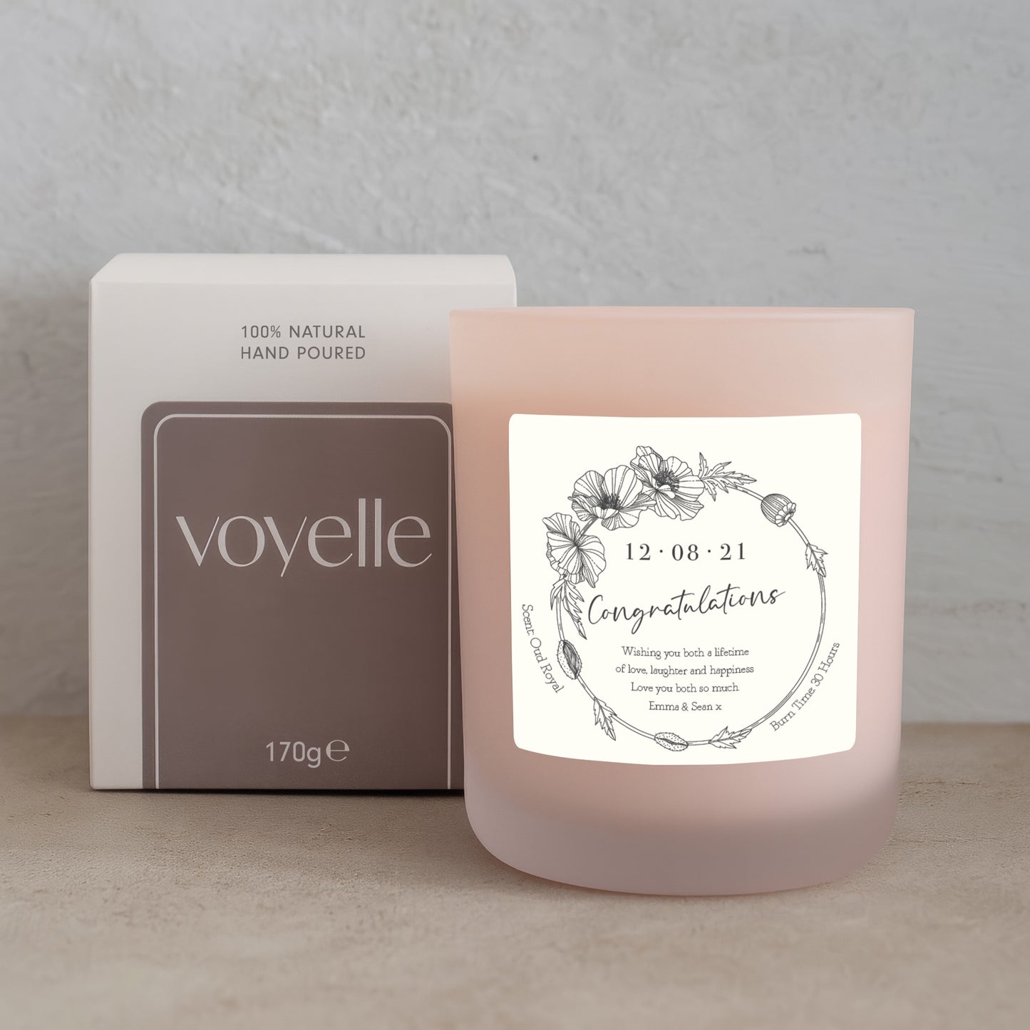 Pink candle with a label and 'voyelle' packaging on a neutral background