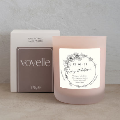 Pink candle with a label and 'voyelle' packaging on a neutral background