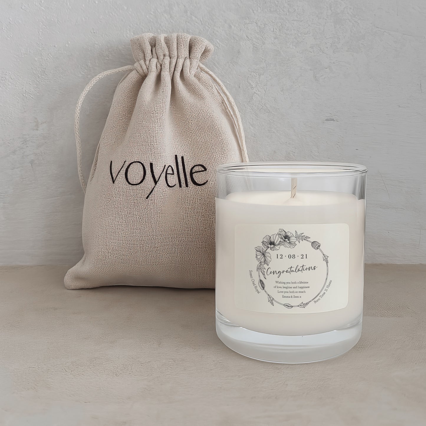 Candle with a label and 'voyelle' drawstring bag on a neutral background