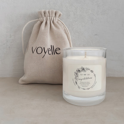 Candle with a label and 'voyelle' drawstring bag on a neutral background