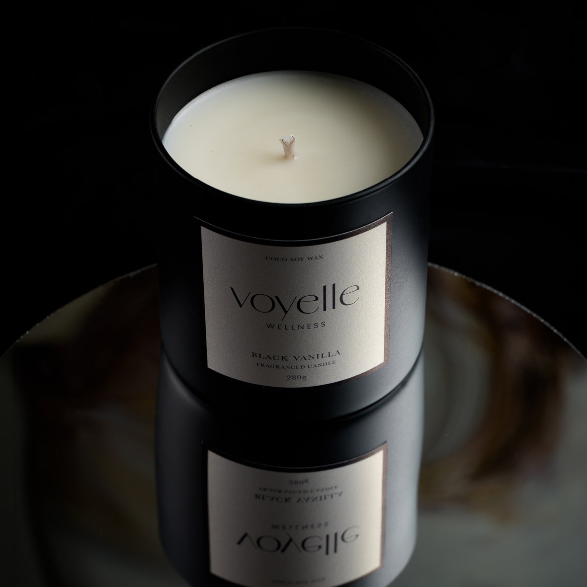 Black Vanilla candle from above on a mirror in moody light