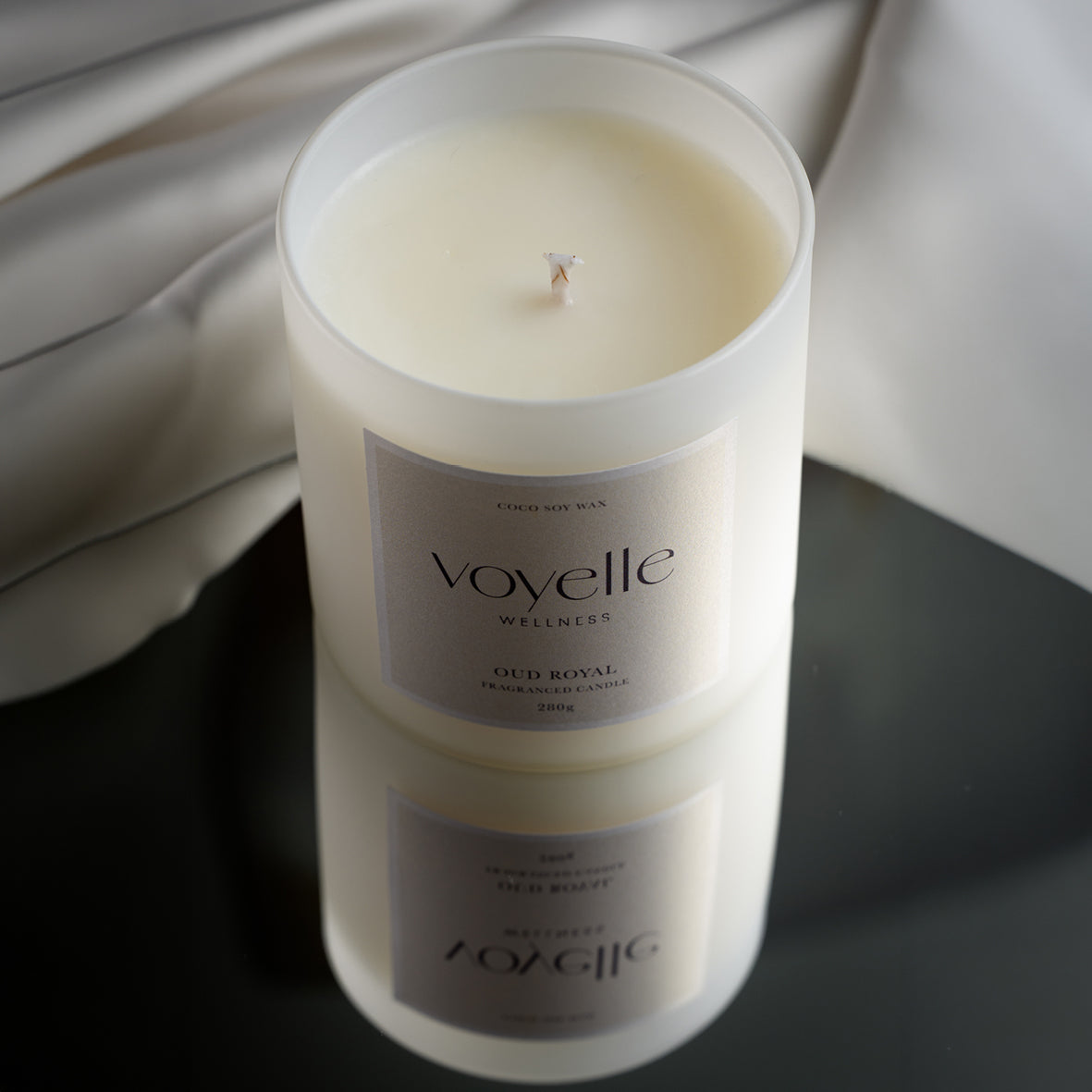 Oud Royal candle on a glossy black table with ivory silk backdrop
