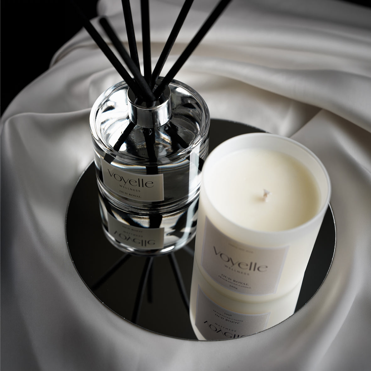 Oud Royal reed diffuser and candle on a round black mirror