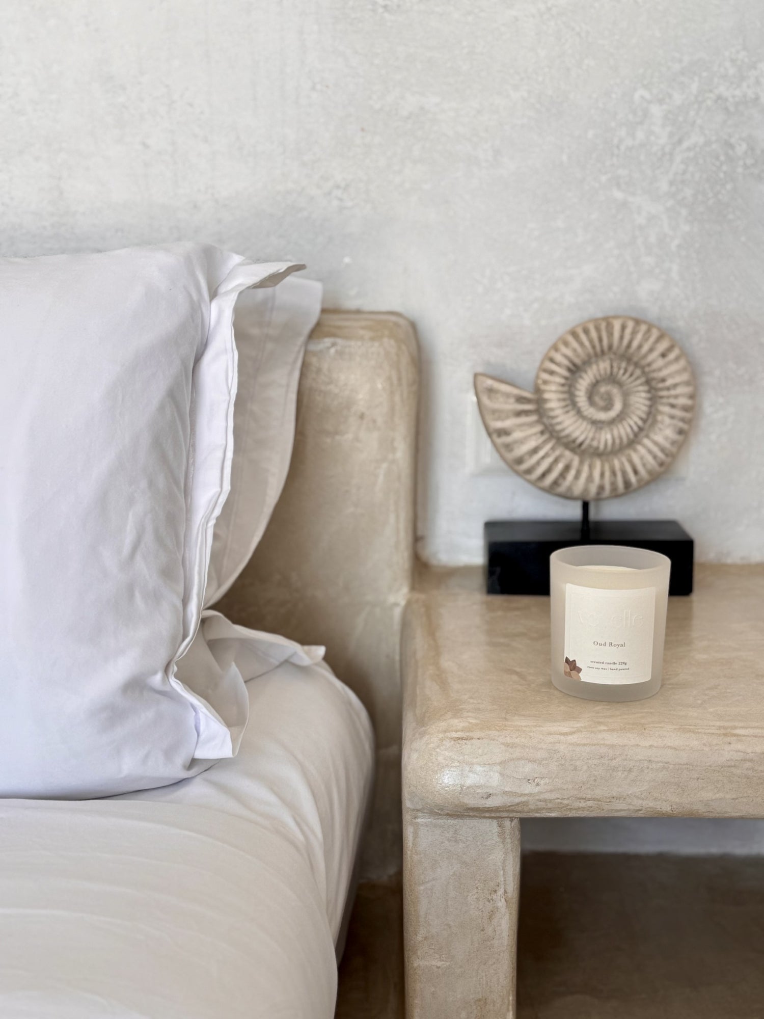 Soy wax candle "Oud Royal" on a stone bedside table in a minimalist bedroom setup – Voyelle handmade scented candle